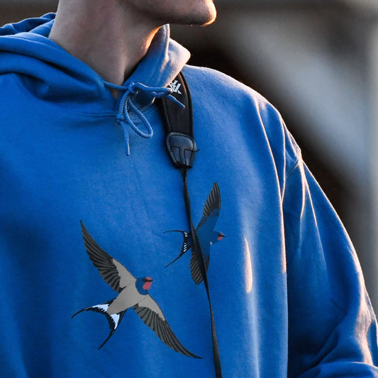 Person wearing a blue hoodie with bird designs, blurred background